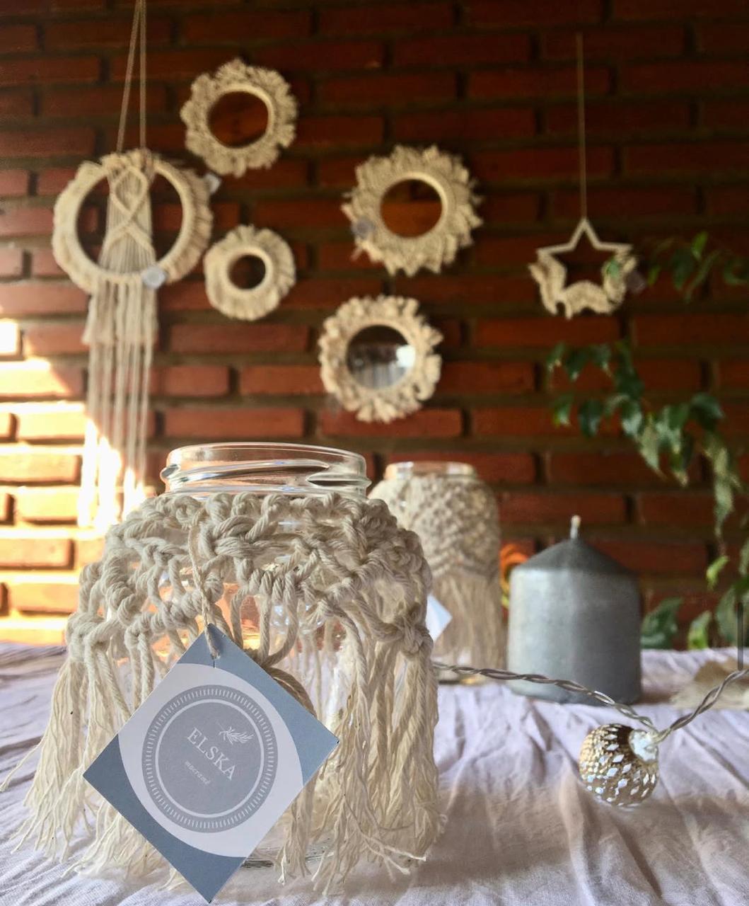 Espejos, fanales y colgantes de macramé sobre una pared de ladrillo